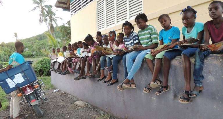 Photo d'enfants qui lisent a cote d'une bibliomoto à Haiti