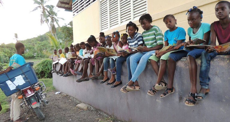 Photo d'enfants qui lisent a cote d'une bibliomoto à Haiti